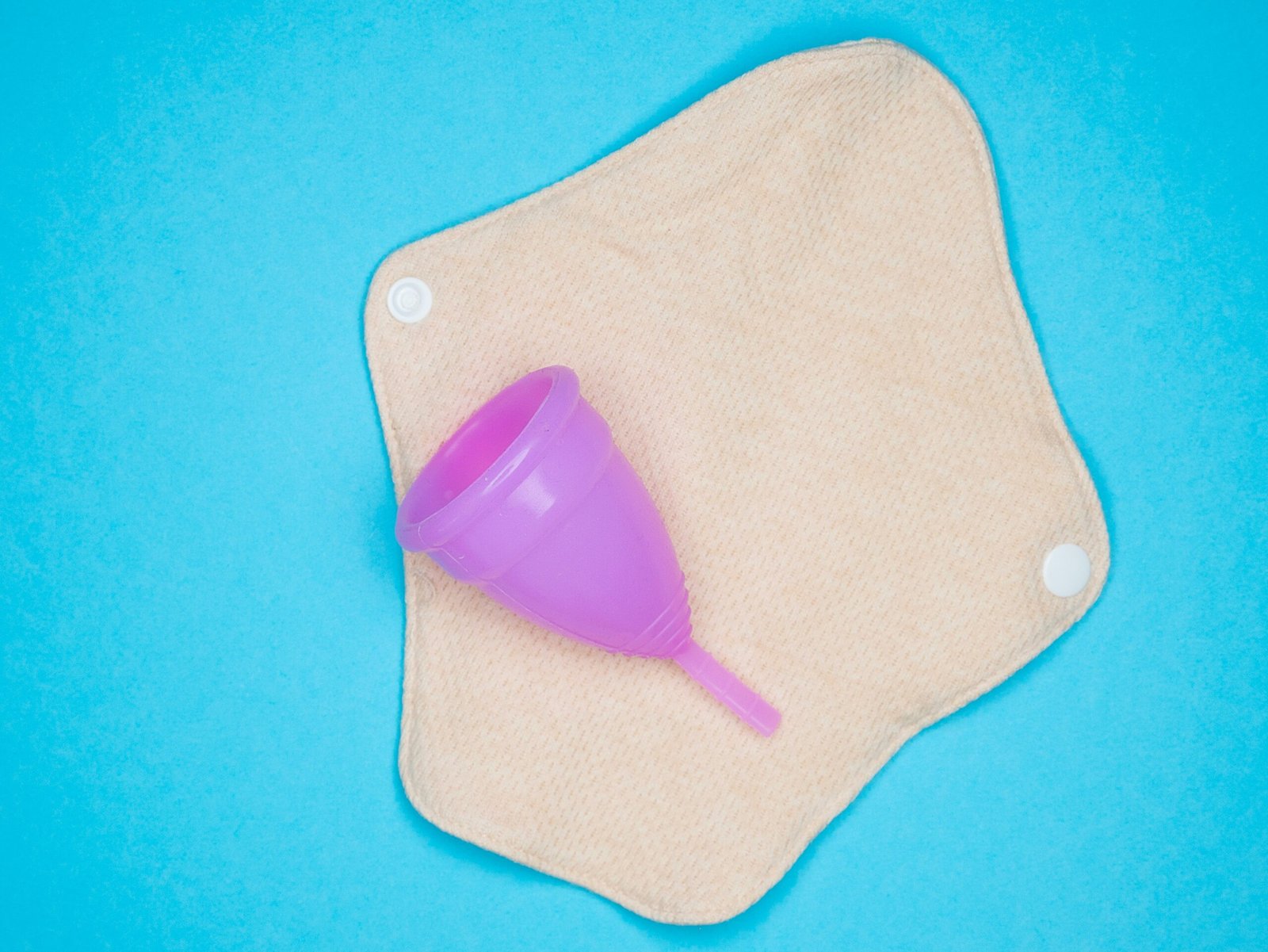 Menstrual health products and supplies (pads, tampons, menstrual cups or reusable cups) on a colorful background.