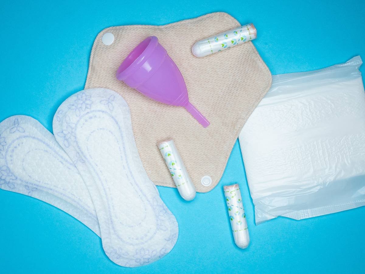 Side-by-side infographic: Conventional pad contains plastic backing, synthetic absorbent core, and fragrance vs. organic pad with GOTS-certified cotton, compostable cellulose, and no added scent