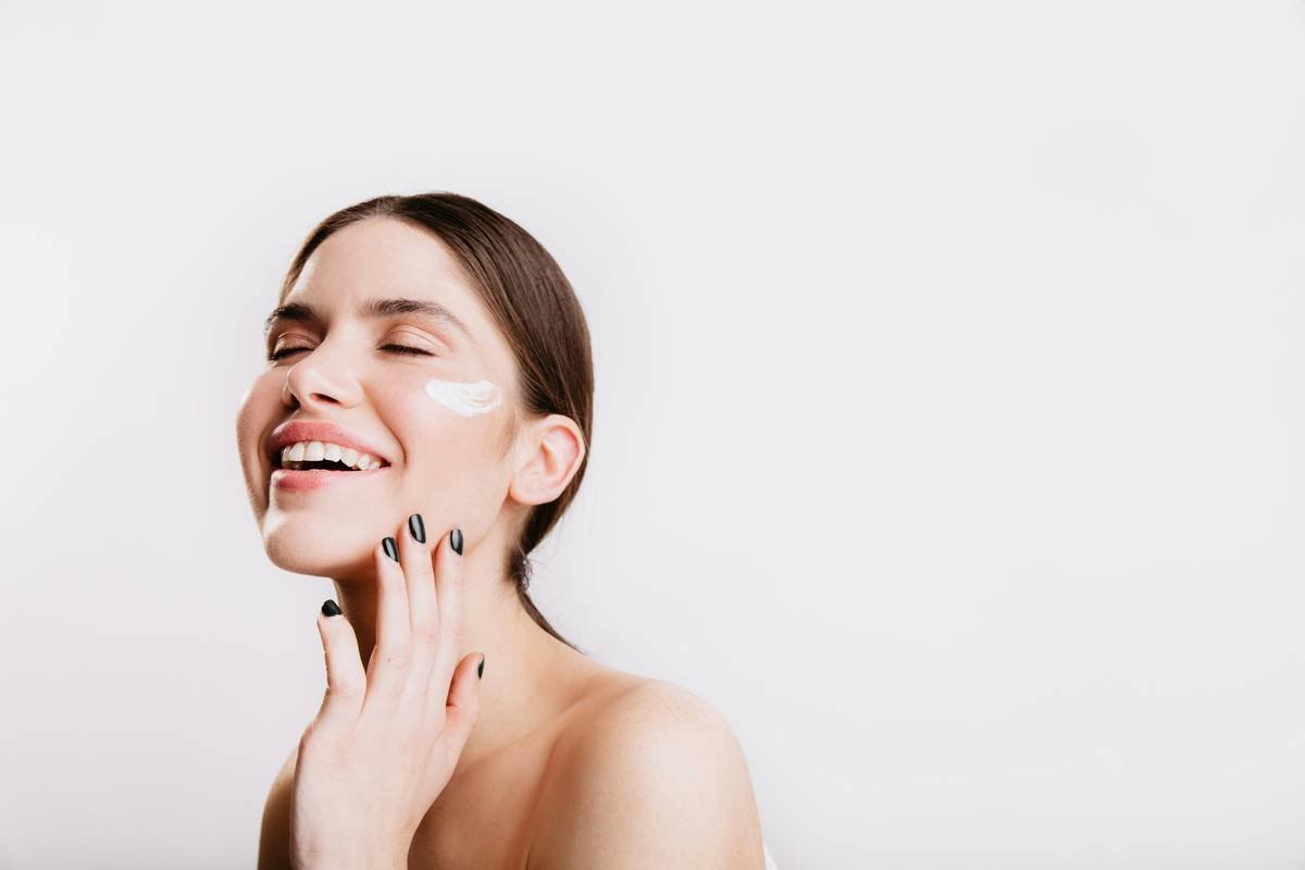 A woman smiles while she holds her hand to her face