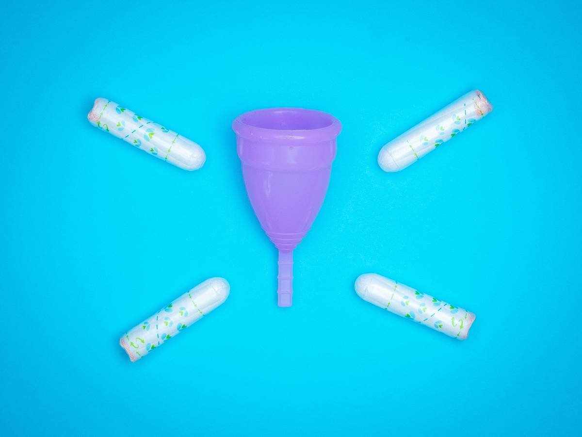 Menstrual products and supplies (pads, tampons, menstrual cups) on a colorful background.