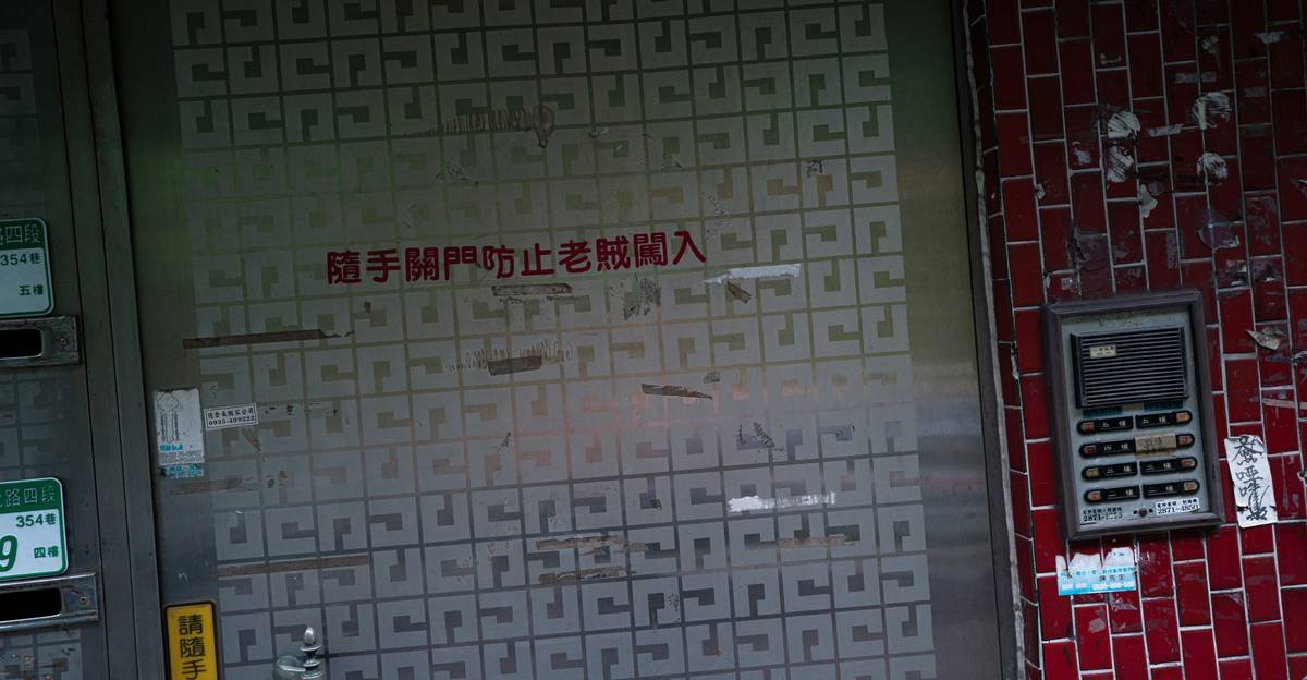 Metal door covered in small square labels and a keypad.