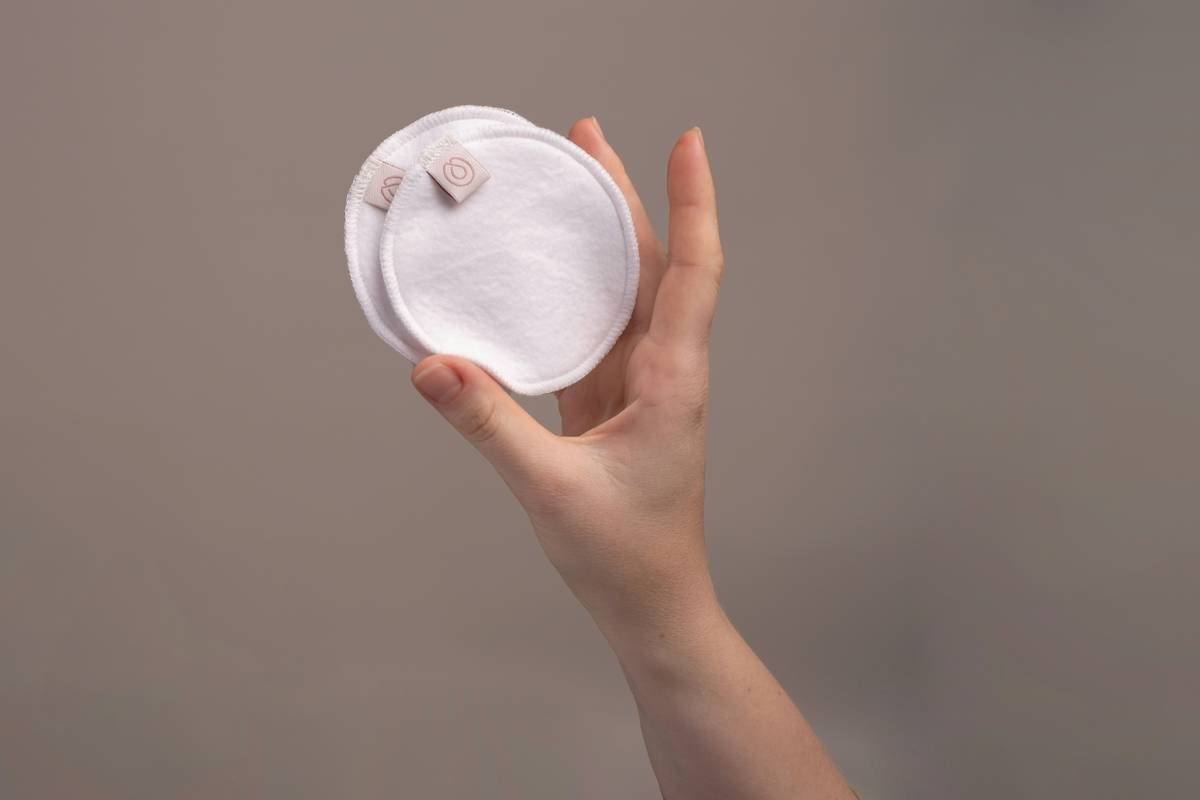 Side-by-side infographic comparing materials in a friendly organic pad vs. conventional pad: organic cotton top layer, compostable core, plant-based backing vs. plastic, SAP, synthetic fibers